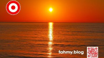 Morgendämmerung am Strand. Die über dem Horizont aufsteigende Sonne tüncht den Himmer und das Wasser in sattem kräftigem Rot. Das rot-weiß-rote Logo von fahmy.blog ist in der linken oberen Ecke, der QR-Code und Bildunterschrift von fahmy.blog ist in der rechten Ecke zu sehen.