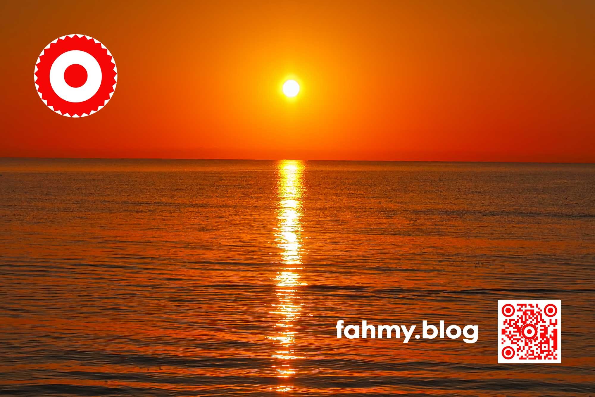 Morgendämmerung am Strand. Die über dem Horizont aufsteigende Sonne tüncht den Himmer und das Wasser in sattem kräftigem Rot. Das rot-weiß-rote Logo von fahmy.blog ist in der linken oberen Ecke, der QR-Code und Bildunterschrift von fahmy.blog ist in der rechten Ecke zu sehen.