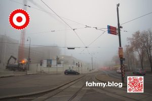 Ende November 2020. Das österreichische Parlament im Umbau. Es ist früh am Morgen. Überall dichter Nebel. Das Parlament ist in nahezu undurchsichtigem Nebel getüncht. Ebenso der angrenzende Ring. Die Pallas Athene kann man hinter den Pallisaden der Großbaustelle erahnen. Nur die Scheinwerfer des Morgenverkehrs, die Signalleuchte am Kranwagen dringen durch den Nebel. Das Bild heißt Baustelle und illustriert den Beitrag Democrazy. Das rot-weiß-rote Logo von fahmy.blog ist in der linken oberen Ecke, der QR-Code und Bildunterschrift von fahmy.blog ist in der rechten Ecke zu sehen.